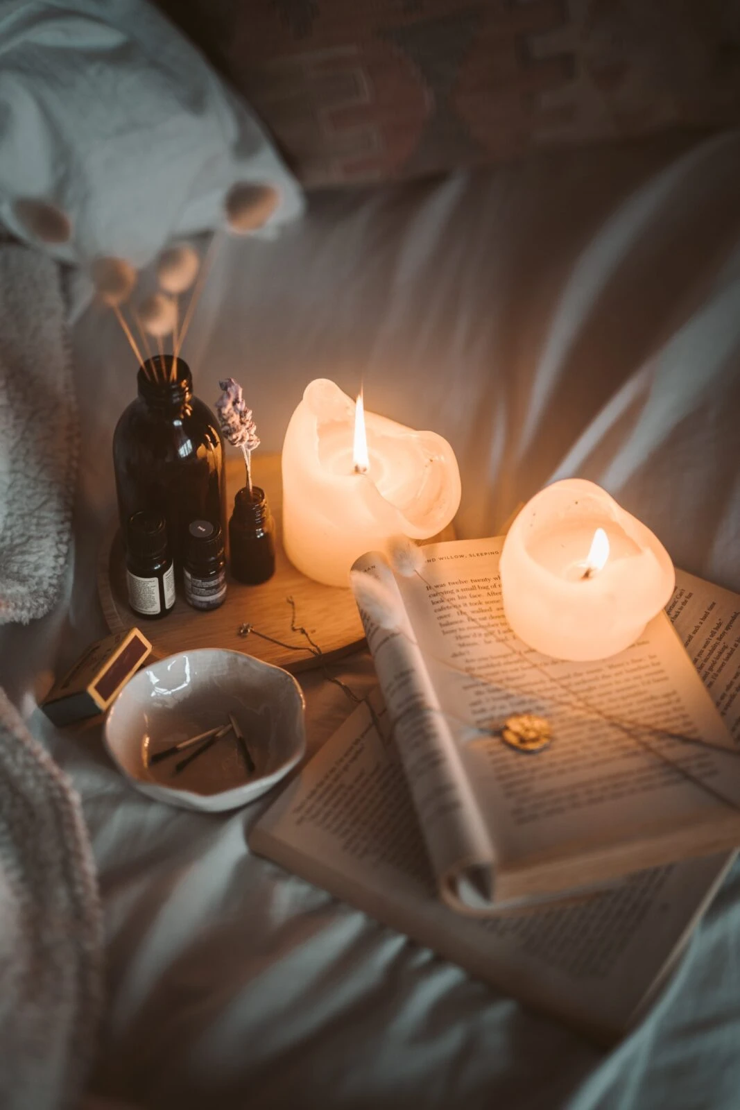 a candle with a book on a bed